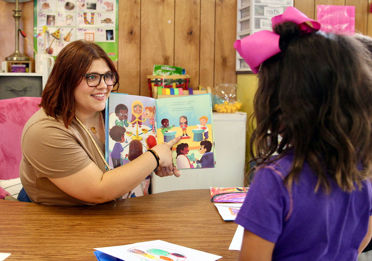 Brushy Creek Elementary teacher showing a book to a student